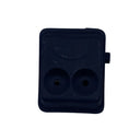 A small black plastic dual-port electrical connector or adapter with two round sockets, placed on a scratched white surface.