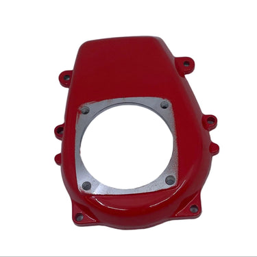 A red plastic engine or motorcycle component cover with a silver metal circular plate, photographed on a scratched white surface.