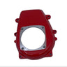 A red plastic engine or motorcycle component cover with a silver metal circular plate, photographed on a scratched white surface.