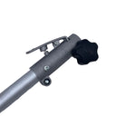 A close-up of a silver metal pole with a black star-shaped adjustment knob and a small metal clip, resting on a scratched white surface.