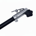 A close-up of a silver metal pole with a black star-shaped adjustment knob and a small metal clip, resting on a scratched white surface.