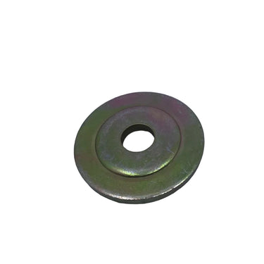 A small circular metal spacer or shim with a center hole, showing a greenish-bronze metallic finish, placed on a scratched light gray surface.