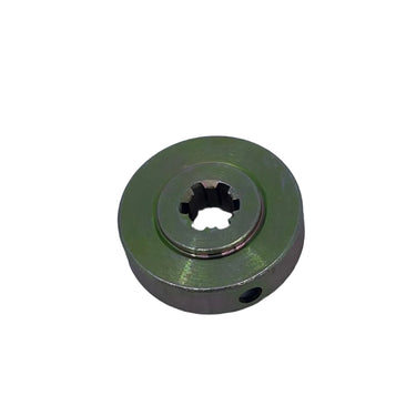 A small circular metal pulley or sprocket with a star-shaped hole in the center, finished in a muted olive green, resting on a scratched light gray surface.