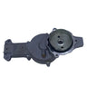 A used metal automotive water pump housing with a pulley and belt cover, photographed on a scratched light gray surface.
