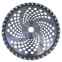 A circular metal circular saw blade with a perforated design and sharp teeth around the edge, photographed from above on a light gray surface.
