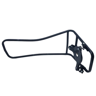 A black metal bicycle frame rack or storage bracket placed inside a white light box or photography backdrop, with a cluttered workshop or storage area visible underneath.