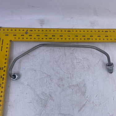 A curved metal automotive part with two bolt holes, shown on a scratched white surface with a yellow tape measure for scale.