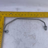 A curved metal automotive part with two bolt holes, shown on a scratched white surface with a yellow tape measure for scale.