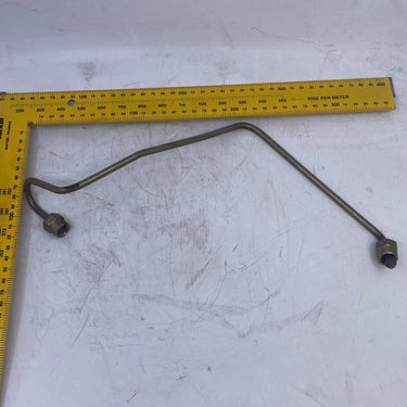 A long, thin metal rod or wire with two small threaded ends, laid out on a white surface next to a yellow L-square ruler for scale.