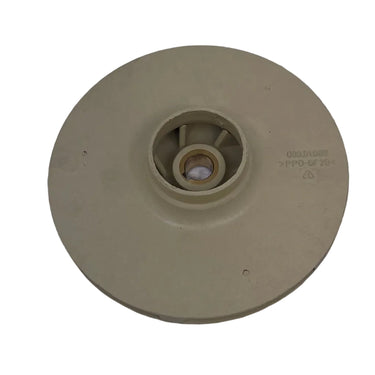 A beige plastic circular component with a central hub, photographed on a scratched light gray surface.