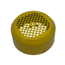 A small round yellow plastic object with a perforated top, photographed on a scratched white surface.