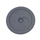 A round gray plastic or rubber disc with a central hole and a small curved marking, photographed from above on a scratched light gray surface.