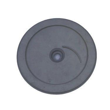 A round gray plastic or rubber disc with a central hole and a small curved marking, photographed from above on a scratched light gray surface.