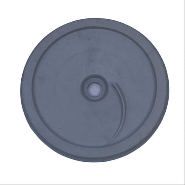A circular gray plastic component with a central hole and a small curved slot, shown on a scratched light gray surface.