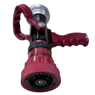 A red and black fire hose nozzle with a red loop handle, resting on a light wood-grained tabletop.